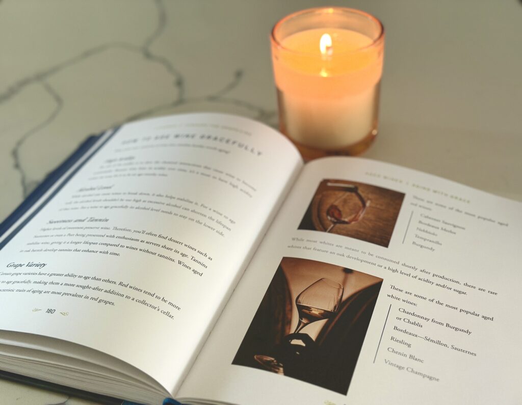 the I learned it through the grapevine wine book open on a white counter top next to a lit candle